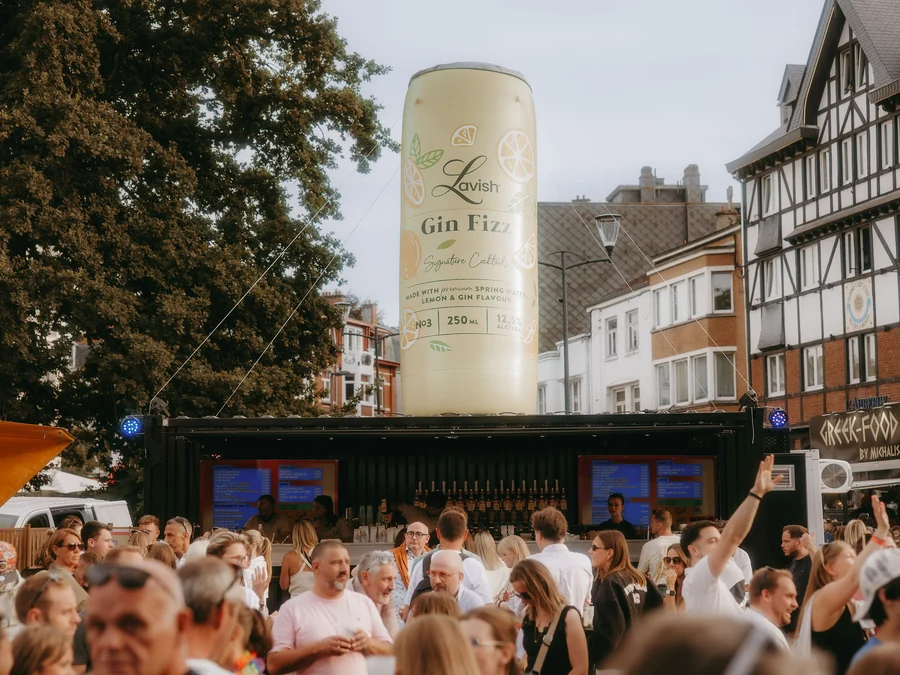 Giant inflatable Lavish Gin Fizz can above a branded shipping-container bar at an outdoor event